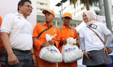 Direktur Utama Telkom Alex J.Sinaga (paling kiri) dan Direktur Consumer Service Telkom Siti Choiriana (paling kanan) bersama dengan perwakilan Pasukan Oranye DKI Jakarta penerima bantuan Paket Sembako saat Jalan Sehat 7.300 m BUMN Hadir untuk Negeri 2018 di Jakarta, Ahad (19/8).