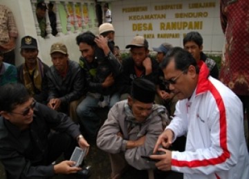 Direktur Utama Telkomsel Sarwoto Atmosutarno mengedukasi penduduk Ranu Pane menggunakan ponsel disaksikan Sekjen Kominfo Basuki Yusuf Iskandar.