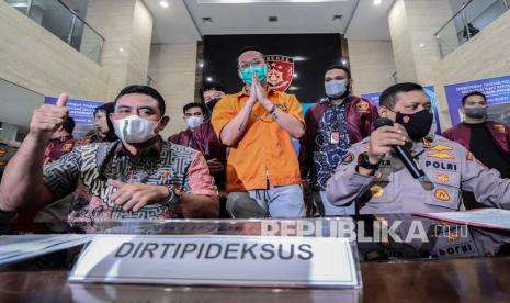 Dirtipideksus Bareskrim Polri Brigjen Whisnu Hermawan (kiri) bersama Kabag Penum Divisi Humas Polri Kombes Pol Gatot Repli Handoko (kanan) memberikan keterangan kepada media saat gelar barang bukti kasus afiliator Binomo dengan Tersangka Indra Kesuma atau Indra Kenz (tengah) di Bareskrim, Mabes Polri, Jakarta. Dalam acara tersebut petugas kepolisian menghadirkan sejumlah barang bukti berupa uang sejumlah Rp 1,24 miliar serta mobil Tesla Model 3.