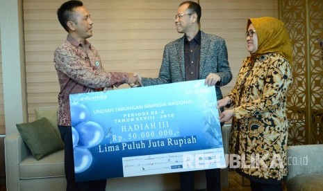 Dirut Bank BJB Ahmad Irfan (kedua kanan) di dampingi Direktur Retail & Konsumer Bank BJb Suartini (kanan) secara simbolis menyerahkan hadiah undian Simpeda Periode Ke-2 Tahun 2018 kepada pemenang ketiga Enang, di Kantor Bank BJB, Jalan Naripan, Kota Bandung, Kamis (12/4). 