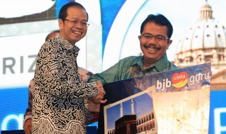 Dirut Bank BJB Ahmad Irfan (kiri) menyerahkan secara simbolik grandprize berupa wisata religi dalam ajang penarikan Undian BJB Cinta Guru di Intercontinental Hotel, Dago Resort Bandung, Rabu (1/2) malam. 