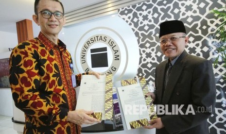 Dirut Bank Syariah Bukopin (BSB) Saidi Mulia Lubis (kiri) dan Rektor Unisba Prof Edi Setiadi (kanan) memgang perjanjian kerjasama usai penandatanganan MoU tentang pemanfaatan produk dan jasa penbankan syariah milik BSB, di Gedung Rektorat Unisba, Kota Bandung, Kamis (19/4).