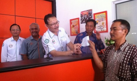 Dirut BPJS Kesehatan Fachmi Idris (tengah) menyerahkan bukti pembayaran dengan sistem payment point online bank (PPOB) di Kantor Pos Congeang, Kabupaten Sumedang, belum lama ini. 