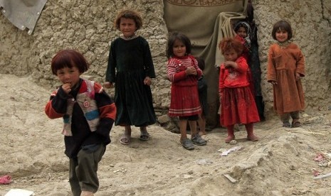 Displaced Afghan children stand near their shelter at a refugee camp in Kabul, May 9, 2012.   