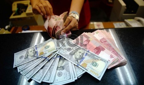 Dollar Naik, Rupiah Turun: Petugas menghitung uang pecahan 100 Dollar dan uang pecahan Rp. 100 ribudi salah satu tempat penukaran uang, Jakarta, Kamis (12/2).