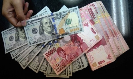 Dollar Naik, Rupiah Turun: Petugas menghitung uang pecahan 100 Dollar dan uang pecahan Rp. 100 ribudi salah satu tempat penukaran uang, Jakarta, Kamis (12/2).