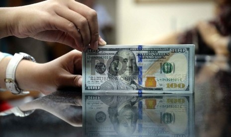 Dollar Naik, Rupiah Turun: Petugas menghitung uang pecahan 100 Dollar dan uang pecahan Rp. 100 ribu di salah satu tempat penukaran uang, Jakarta, Kamis (12/2).