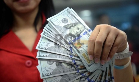 Dollar Naik, Rupiah Turun: Petugas menghitung uang pecahan 100 Dollar dan uang pecahan Rp. 100 ribu di salah satu tempat penukaran uang, Jakarta, Kamis (12/2).