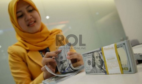 Dollar Semakin Menguat: Teller menghitung dollar di Banking Hall Bank Mandiri, Jakarta, Rabu (11/3).