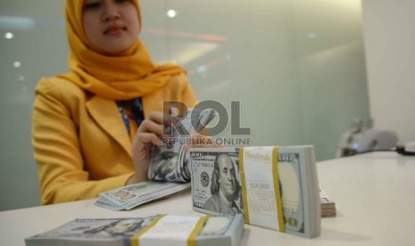 Dollar Semakin Menguat: Teller menghitung dollar di Banking Hall Bank Mandiri, Jakarta, Rabu (11/3).