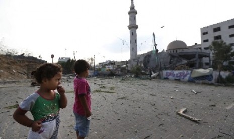 Dua anak di Jalur Gaza melihat bangunan di sekitarnya hancur diserang militer Israel.