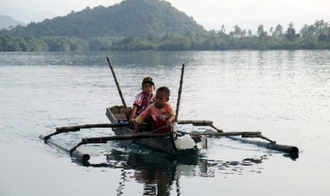 Anak nelayan mendayung perahu 