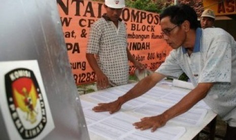 Dua anggota KPPS menyiapkan Tempat Pemungutan Suara (TPS).