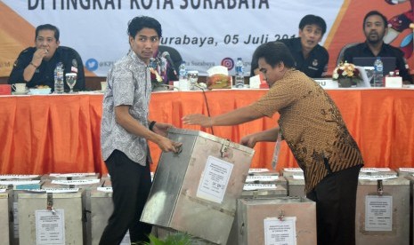 Dua anggota Panitia Pemilihan Kecamatan (PPK) mengangkat kotak suara ketika Rapat Pleno Rekapitulasi Penghitungan Suara Pilgub Jatim 2018 di Kantor Komisi Pemilihan Umum (KPU) Surabaya, Jawa Timur, Kamis (5/7). 