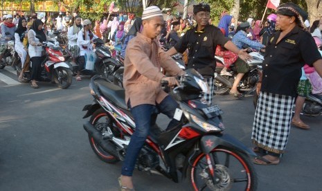 Survei Kerukunan, Kemenag: Semua Daerah Rukun dan Toleran. Foto ilustrasi dua anggota Pecalang atau satuan pengamanan adat Bali mengatur lalu lintas saat pelaksanaan shalat Idul Adha di Lapangan Lumintang Denpasar.