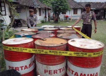 Dua anggota polisi menyegel drum-drum berisi BMM selundupan (ilustrasi).