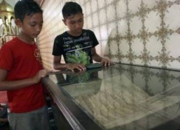 Dua bocah lelaki tengah melihat koleksi Al Quran besar di Masjid Raya Al Mashun, Medan, Sumatera Barat