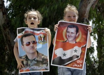 Dua gadis cilik Suriah memegang poster Bashar Al-Assad dalam demonstrasi mendukung sang presiden di depan kedutaan besar Rusia di Beirut, Lebanon, Ahad (19/6).