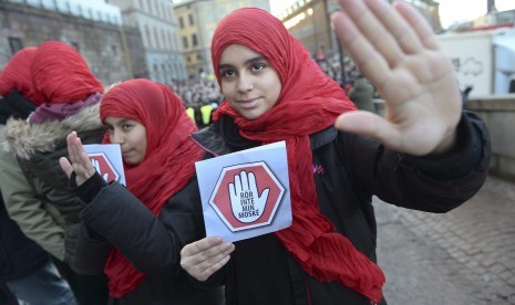 Dua gadis muda membawa selembaran 'jangan sentuh masjidku' sebagai bentuk protes terhadap aksi pelecehan terhadap masjid-masjid di Stockholm, Swedia, pada 2 Januari 2015. 