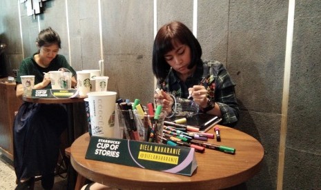 Dua ilustrator sedang menggambar dengan kanvas gelas Starbucks di peluncuran kampanye Starbucks Cup of Stories di Senayan, Jakarta.