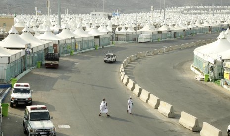 Dua jamaah menyeberangi jalan di dekat tenda jamaah haji di Arafah, Selasa (29/8).