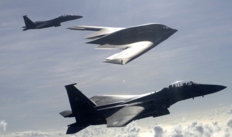 Dua jet tempur F-15 E Eagle bersama pesawat pengebom B-2 dalam formasi udara.