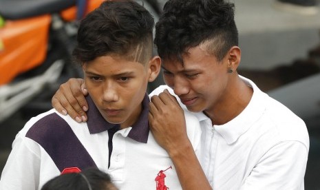 Dua orang adik menunggu jenazah kakak mereka yang tewas dalam kerusuhan penjara di Manaus, Brazil, Selasa (28/5).