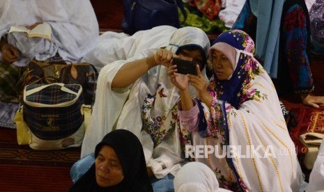 Dua orang akhwat berswafoto sebelum melaksanakan Shalat Idul Adha di Masjid Istiqlal, Jakarta, Senin (12/9). 