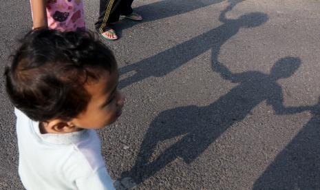 Dua orang anak berjemur bersama orang tuanya. ilustrasi