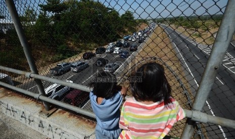 Dua orang anak menonton ribuan kendaraan yang terjebak kemacetan di ruas Jalan Tol Palimanan-Kanci KM 204 hingga gerbang tol Palimanan KM 188 Jalan Tol Cipali, Cirebon, Jawa Barat.