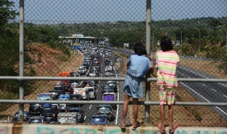 Dua orang anak menonton ribuan kendaraan yang terjebak kemacetan di ruas Jalan Tol Palimanan-Kanci KM 204 hingga gerbang tol Palimanan KM 188 Jalan Tol Cipali, Cirebon, Jawa Barat, Rabu (15/7). H-2 menjelang lebaran diprediksi menjadi puncak arus mudik di 