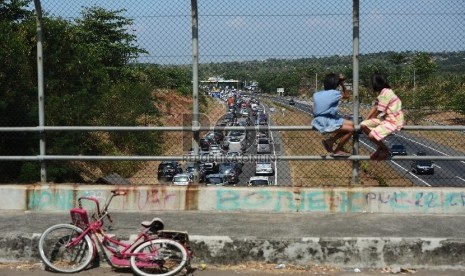 Dua orang anak menonton ribuan kendaraan yang terjebak kemacetan di ruas Jalan Tol Palimanan-Kanci KM 204 hingga gerbang tol Palimanan KM 188 Jalan Tol Cipali, Cirebon, Jawa Barat, Rabu (15/7).