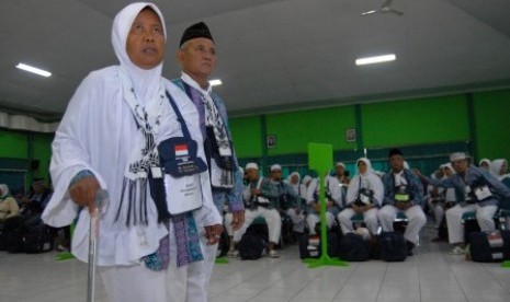 Dua orang calon haji kelompok terbang (kloter) pertama berjalan bersama ketika tiba di Asrama Haji Sukolilo, Surabaya, Jawa Timur, Kamis (20/8). 