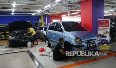 Dua orang mekanik sedang mengecek kondisi mobil yang sedang dipajang di showroom mobil bekasnya di bilangan Kemayoran Jakarta, Selasa (3/10).