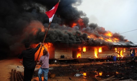  Dua orang melepas tiang bendera di lokasi permukiman warga eks-Gafatar yang dibakar massa di kawasan Monton Panjang, Dusun Pangsuma, Desa Antibar, Mempawah Timur, Kabupaten Mempawah, Kalbar, Selasa (19/1). (Antara/Jessica Helena Wuysang)