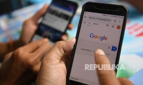 Dua orang membuka laman Google dan aplikasi Facebook melalui gawainya.