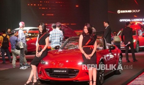 Dua orang model berpose di depan Mazda MX 5 Soft Top.