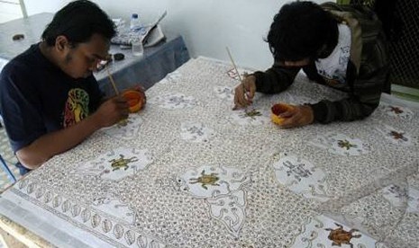 Dua orang pekerja melakukan proses pewarnaan batik tulis di Rumah Batik Jember, Jawa Timur, Kamis (25/11). Dalam sehari setiap pekerja mendapat upah mulai Rp.10.000 - Rp.45.000 tergantung dari motif dan tingkat kesulitan pengerjaan batik.