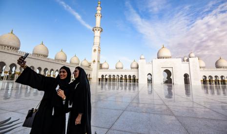 Dua orang perempuan berpose di pelataran Masjid Agung Sheikh Zayed