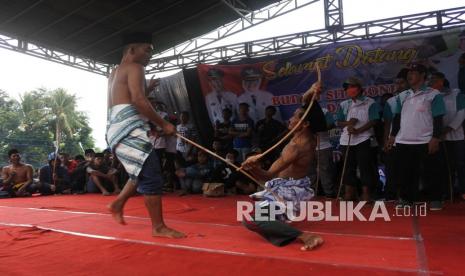 Dua orang peserta kesenian tradisi Ojung saling memukul menggunakan rotan di Desa Bugeman, Kendit, Situbondo, Jawa Timur, Selasa (2/11/2021). Kesenian tradisi Ojung tersebut digelar dalam rangka selamatan desa agar terhindar dari bencana, panen melimpah dan wabah COVID-19 segera berakhir. 