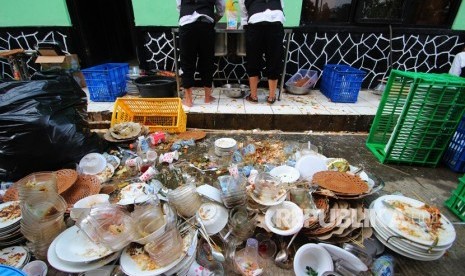 Dua orang petugas catering membersihkan sampah sisa makanan acara resepsi