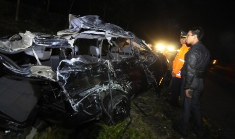 Dua orang petugas melihat bangkai mobil Kijang yang mengalami kecelakaan dengan bus pariwisata di di Tanjakan Emen, Kabupaten Subang, Jawa Barat, Selasa (17/6) malam. 