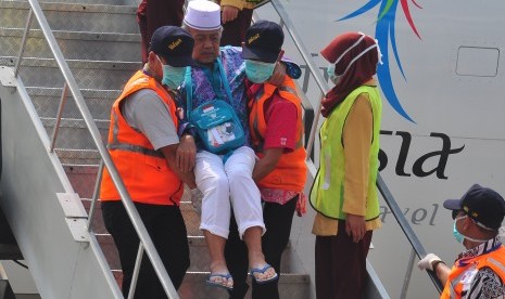 Dua orang petugas membantu jamaah haji saat turun dari pesawat setibanya di Bandara Adi Soemarmo, Boyolali, Jawa Tengah, Kamis (1/10).