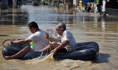  Dua orang pria melintasi genangan air banjir yang menggenangi pemukiman mereka di perumahan Pondok Gede Permai Jatiasih, Bekasi, Selasa (5/2).   (Republika/Rakhmawaty La'lang)