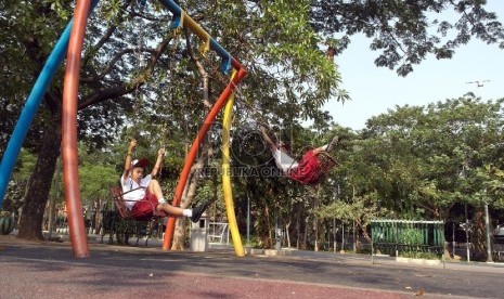 Dua orang siswa SD Nampak bermain ayunan di Taman Menteng Jakarta, Senin (5/10).