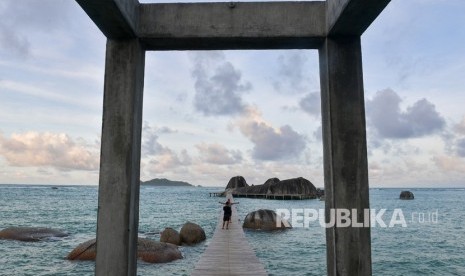 Dua orang wisatawan berfoto di atas jembatan di antara gugusan batu granit di kawasan Sepempang, Natuna, Kepulauan Riau, Ahad (9/2/2020).