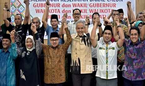 Dua pasangan bakal cagub-cawagub Jawa Tengah Ganjar Pranowo (ketiga kanan, depan)- Taj Yasin (kedua kanan, depan) dan Sudirman Said (ketiga kiri, depan)-Ida Fauziyah (kedua kiri, depan), berfoto bersama sejumlah bakal cabup-cawabup dalam pilkada Jateng, sebelum menjalani tes kesehatan di RSUP Kariadi Semarang, Jawa Tengah, Jumat (12/1). 