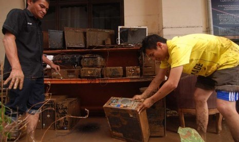   Dua pegawai membersihkan barang elektronik yang penuh lumpur akibat terendam banjir di kantor Walikota Manado, Sulawesi Utara, Kamis (16/1).    (Antara/Fiqman Sunandar)