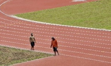 Dua pekerja berjalan di lintasan atletik SEA Games 2011 di Kompleks Olahraga Jakabaring, Palembang. 