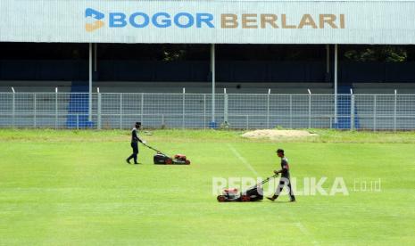 Dua pekerja memotong rumput di lapangan sepakbola Stadion Pajajaran, Kota Bogor, Jawa Barat, Kamis (21/10/2021). Pemerintah Kota Bogor membuka kembali Stadion Pajajaran untuk warga berolahraga dengan melakukan pembatasan kapasitas mencapai 50 persen dan penerapan protokol kesehatan di masa PPKM Level 2.